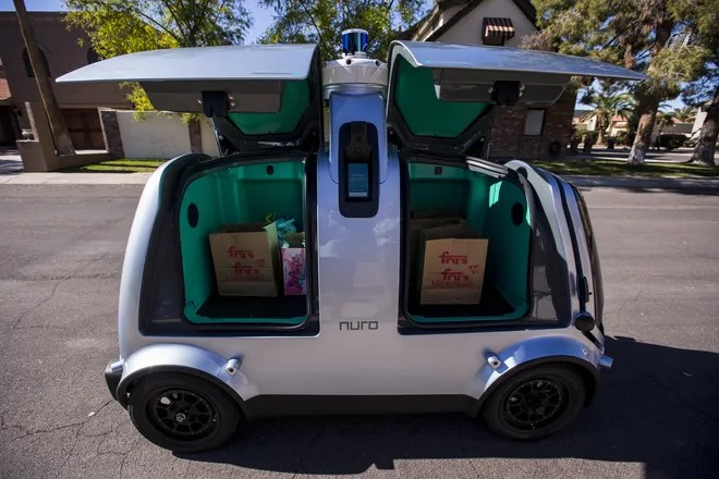 Nuro autonomous delivery pod with its doors open, loaded with grocery bags